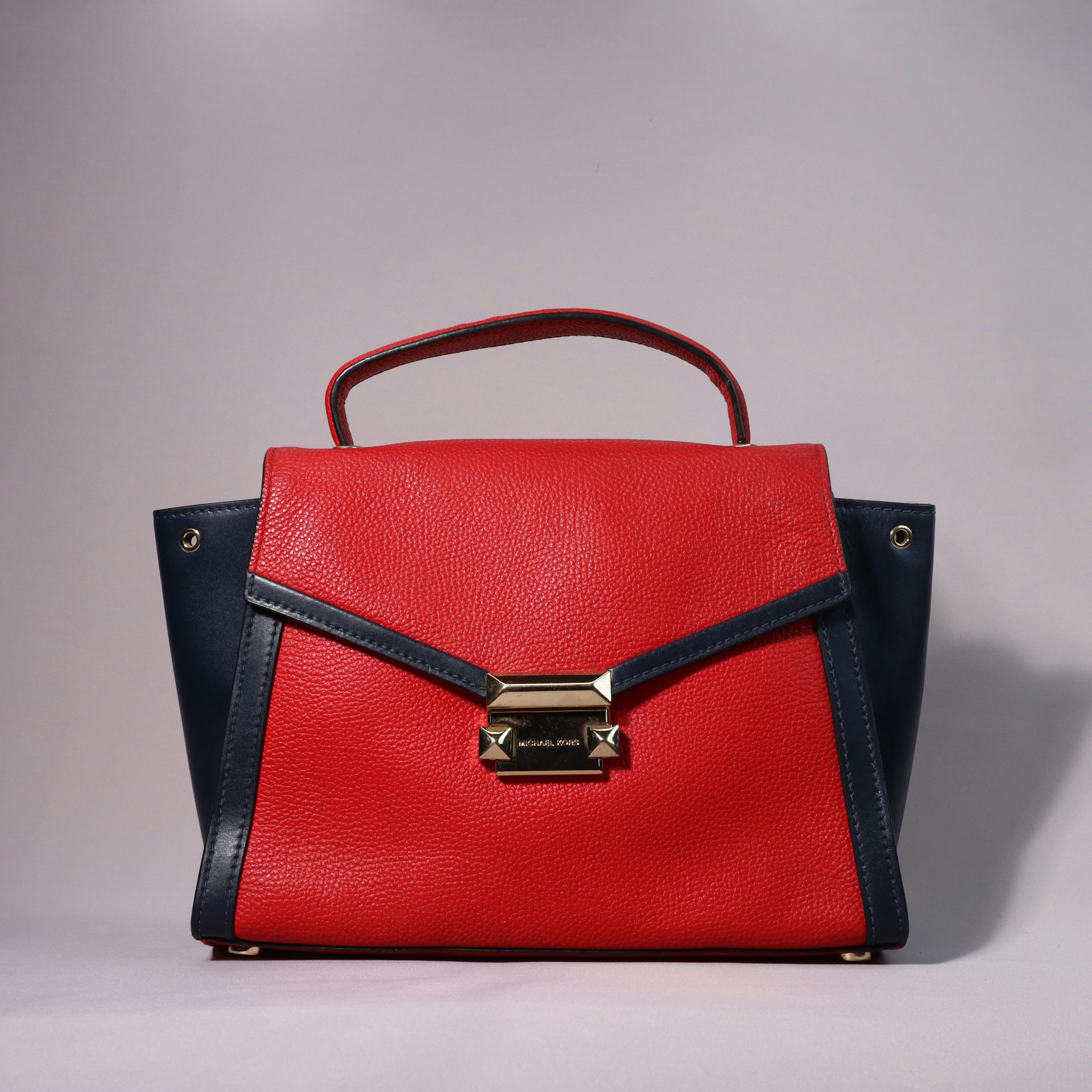 A red and blue handbag sits on a flat surface.